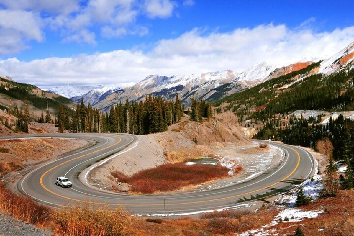a winding road in the mountains with a car on it