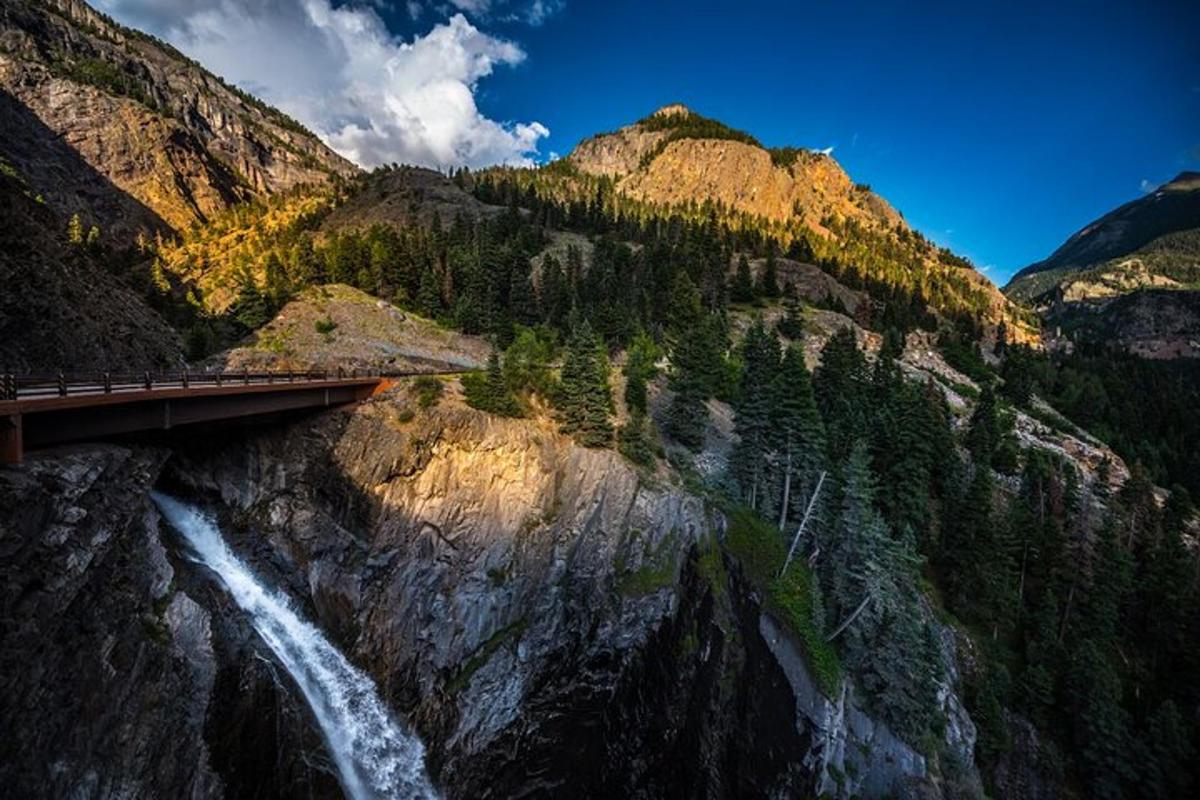 a bridge over a waterfall next to a mountain