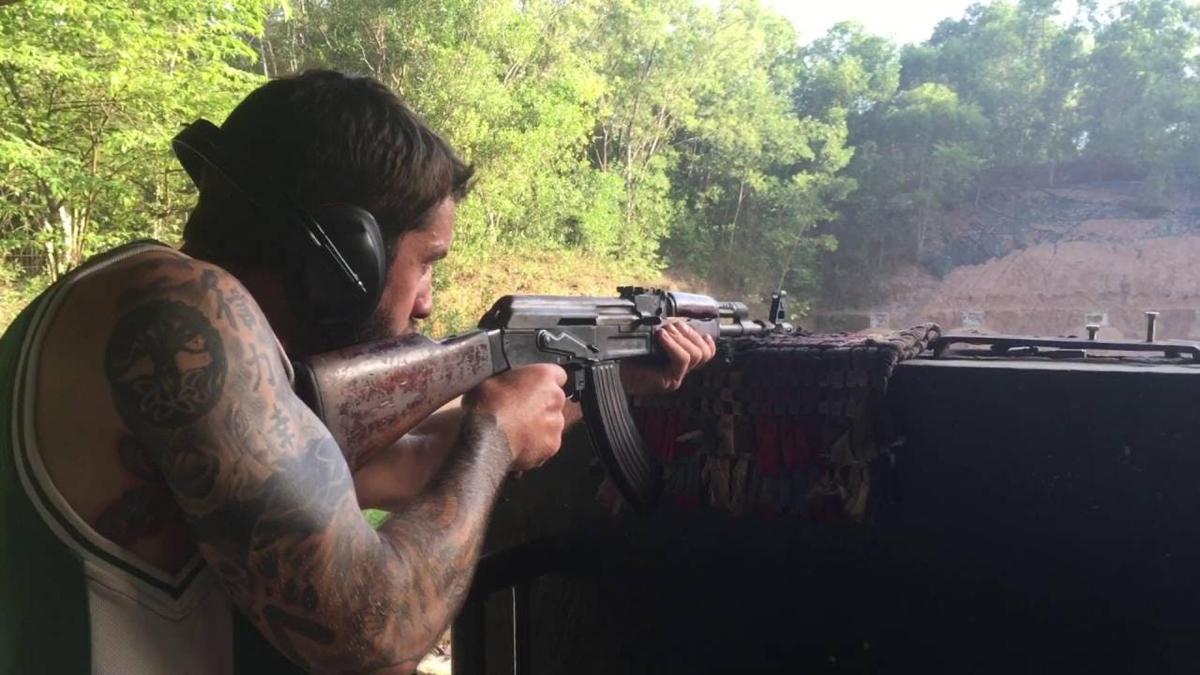 a man with a tattoo holding a machine gun