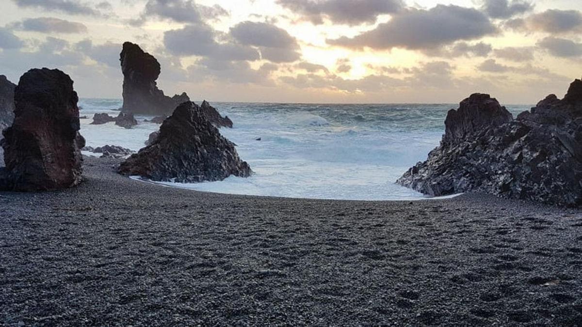 ein Strand mit Felsen im Wasser und dem Meer