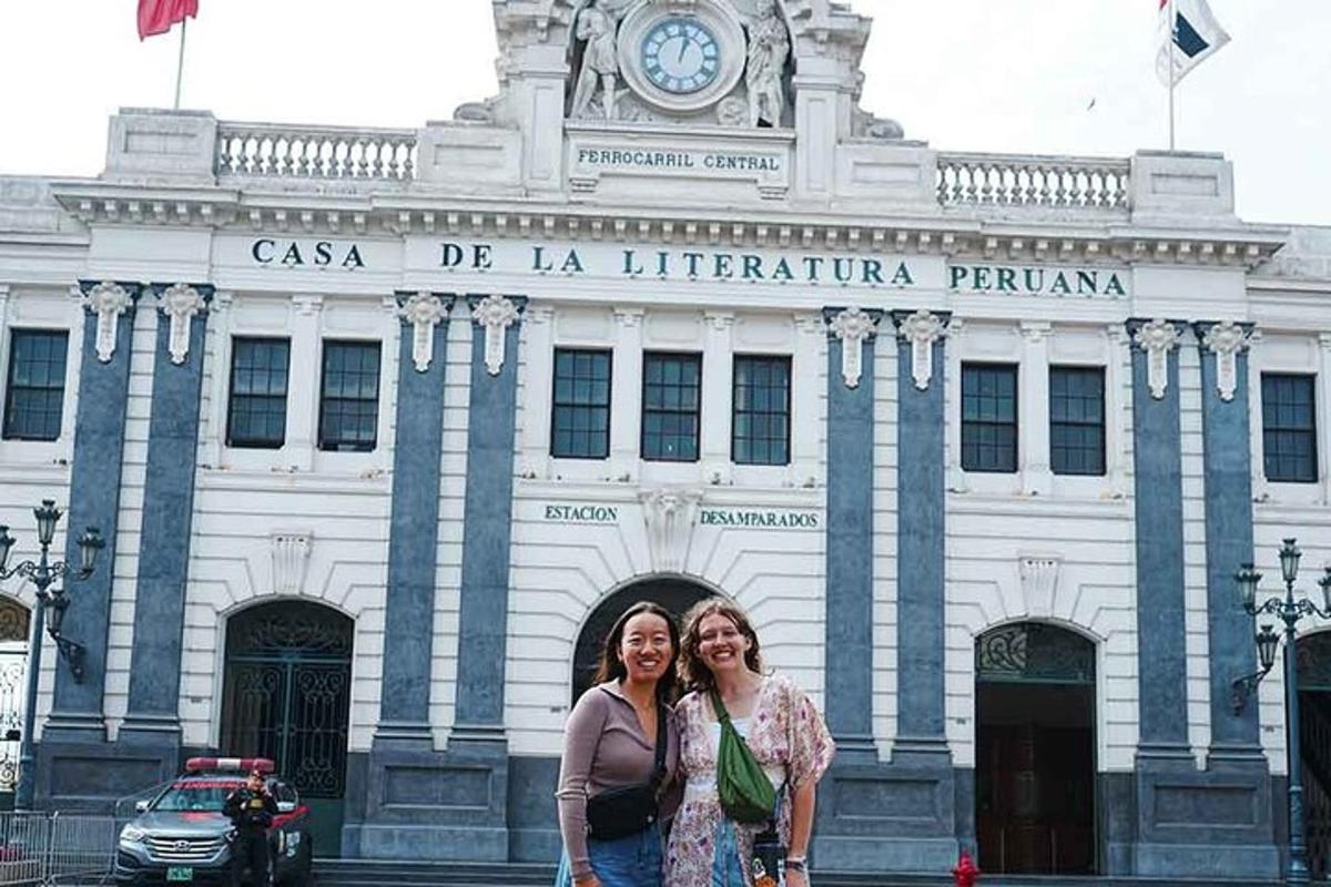 two women standing in front of a building with a clock