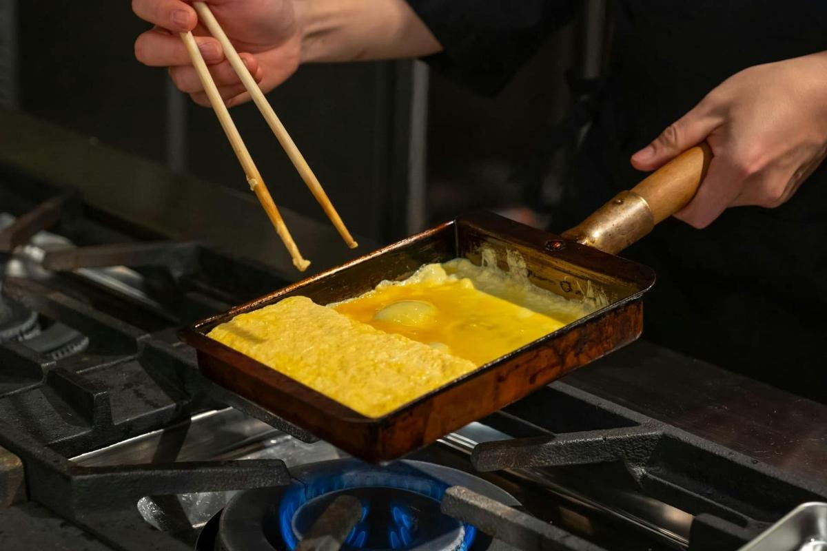 seseorang memasak makanan dalam kuali di atas dapur