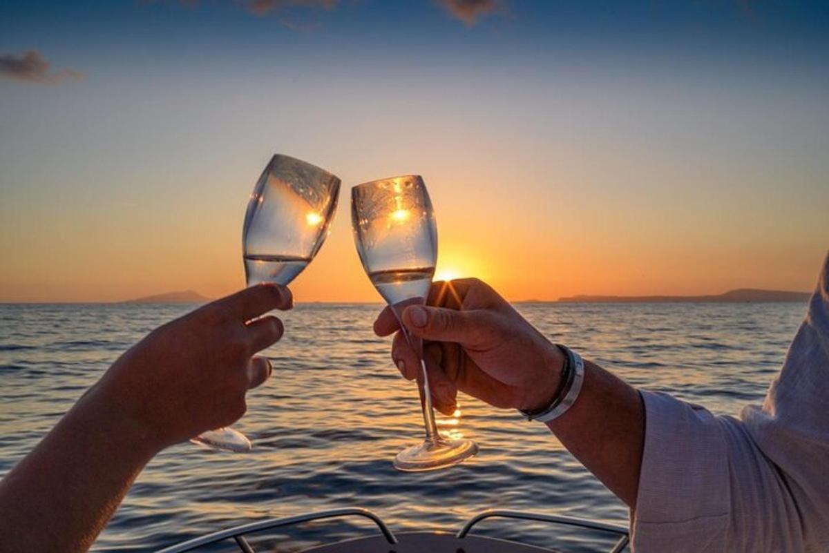 due persone che tengono in mano dei bicchieri di vino di fronte all'oceano