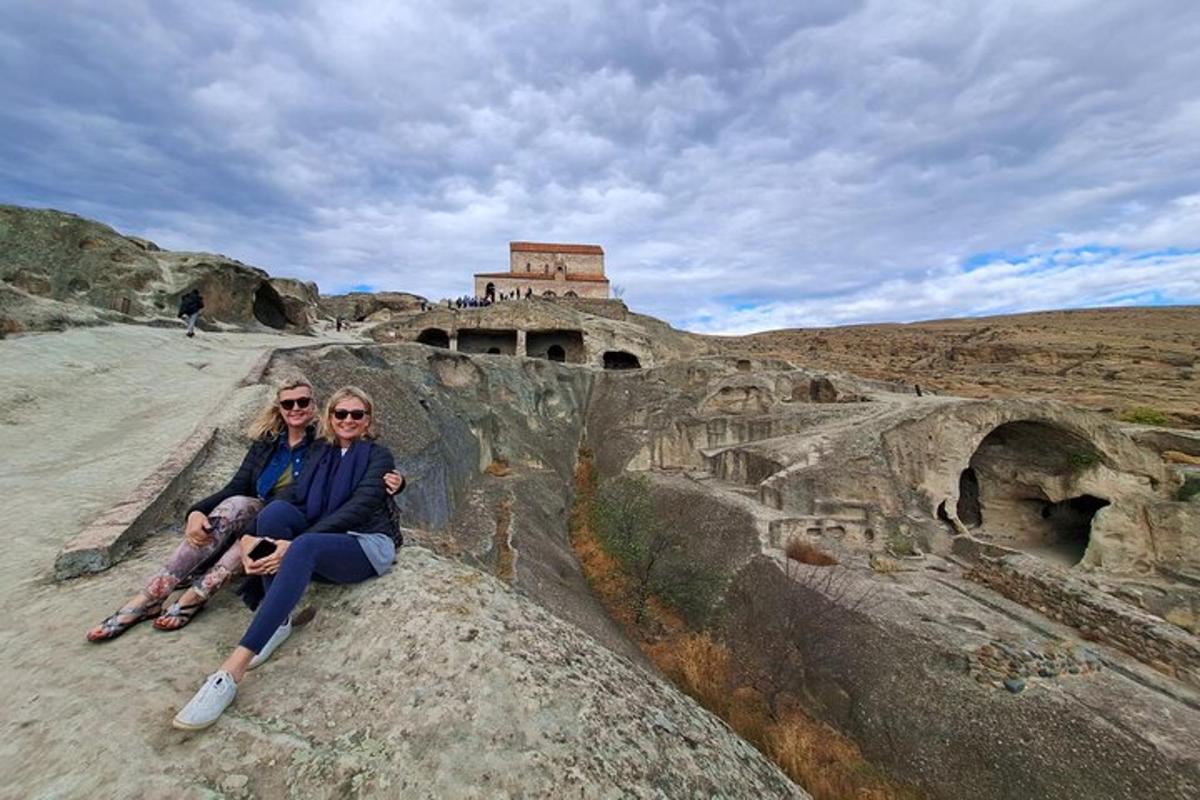 Dos mujeres sentadas en una roca frente a una ruina