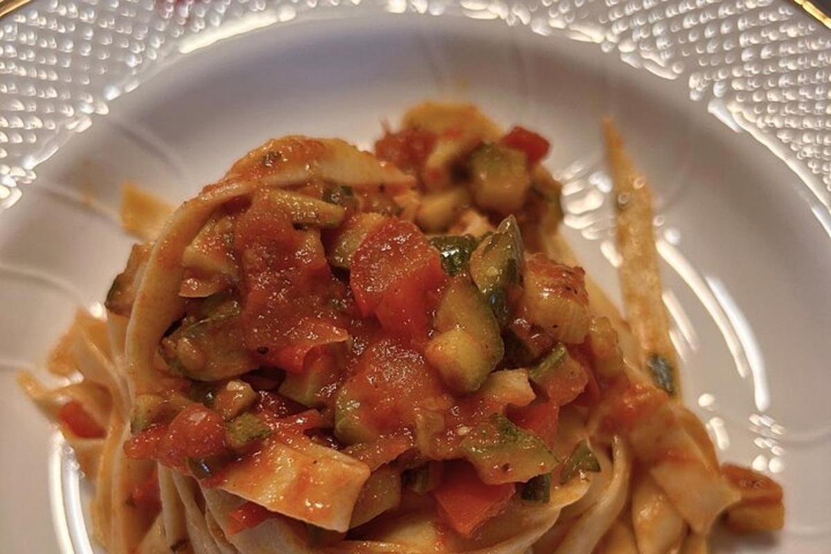 isang puting plato ng pasta na may karne at gulay