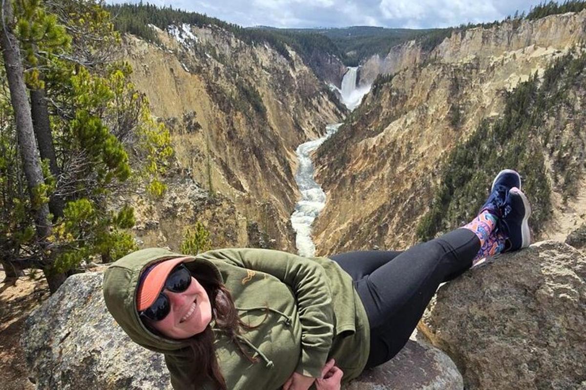 a woman laying on a rock overlooking a waterfall