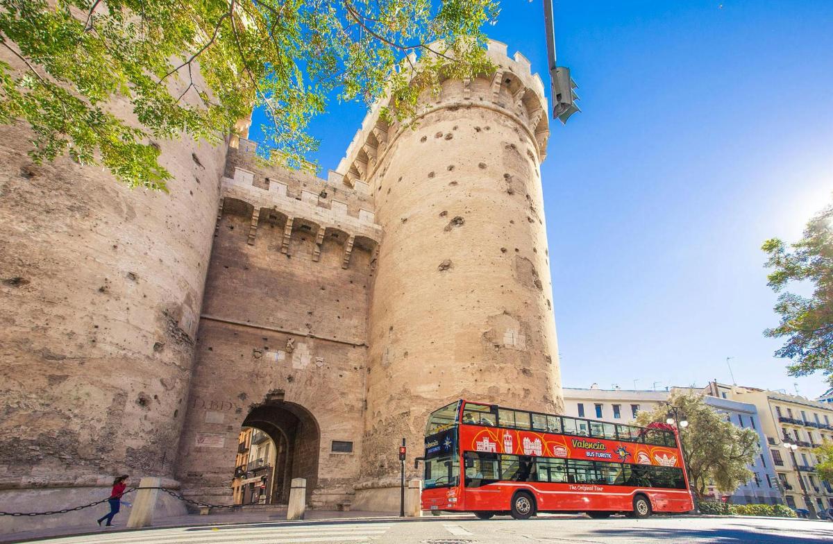 un autobús vermell de dos pisos aparcat davant d'un castell