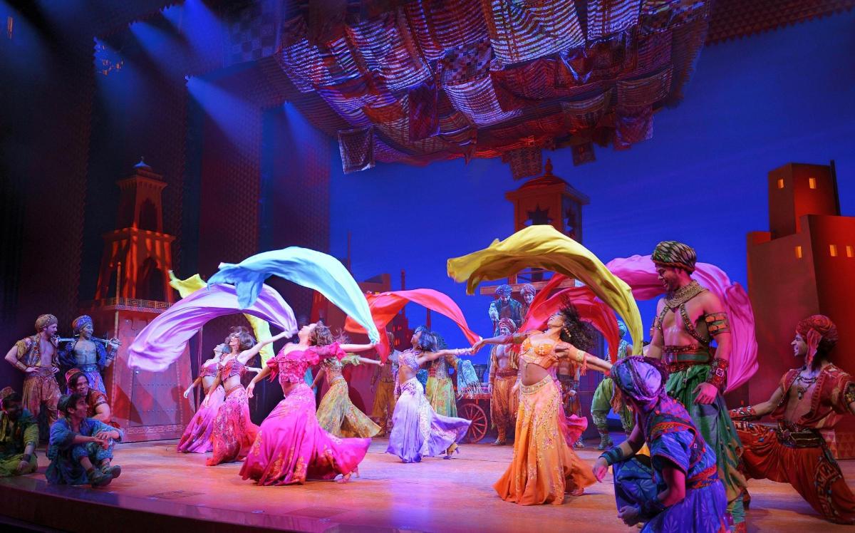 a group of people dancing on a stage with umbrellas