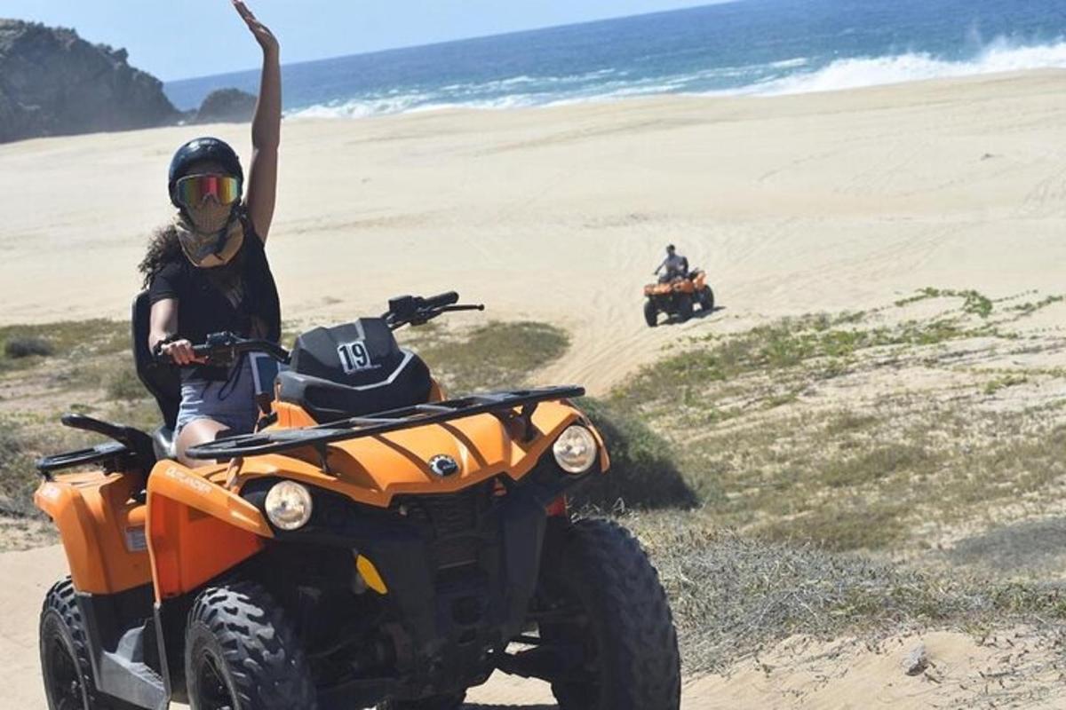 una persona su un quad arancione sulla spiaggia