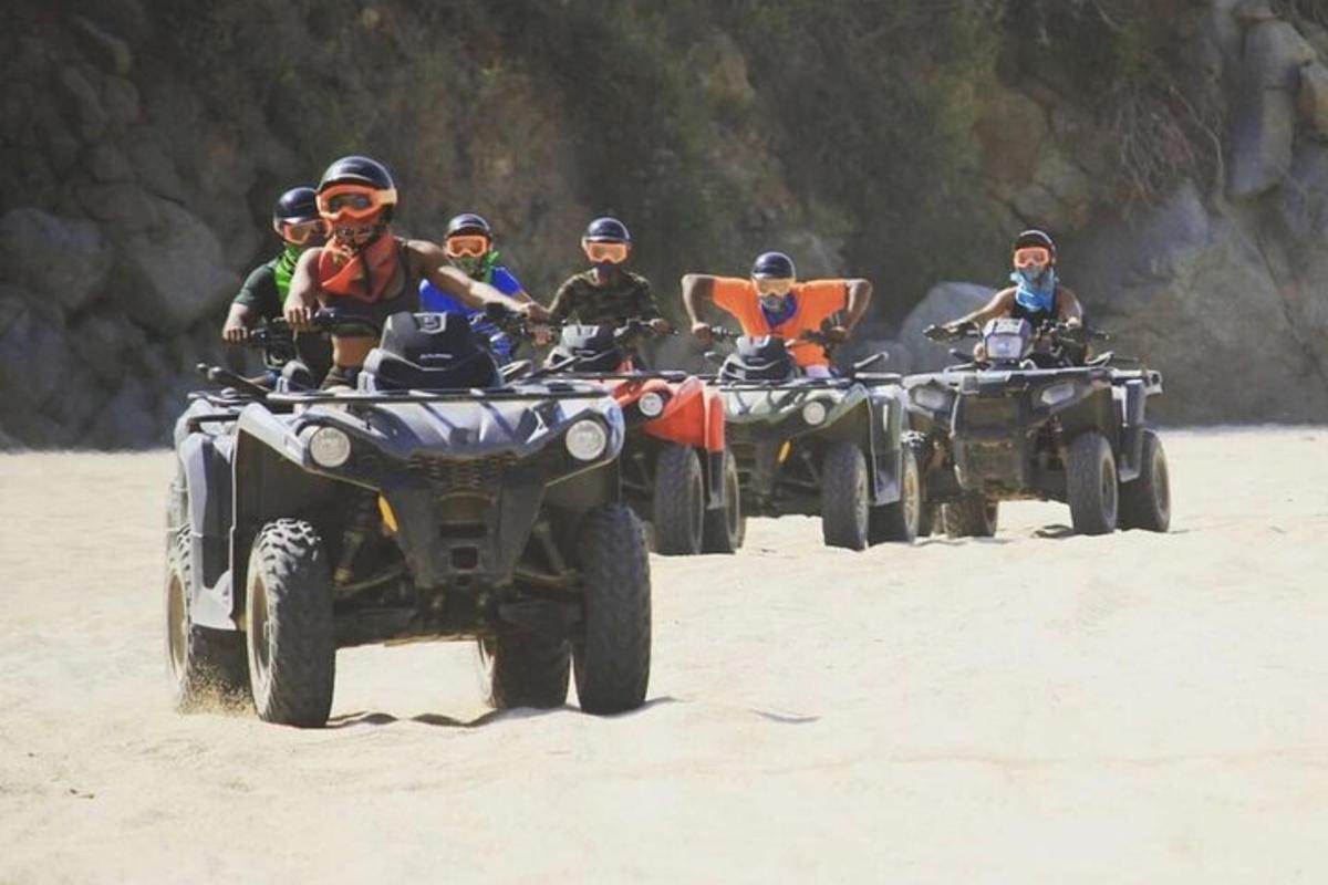 un grup de persones conduint quads a la platja