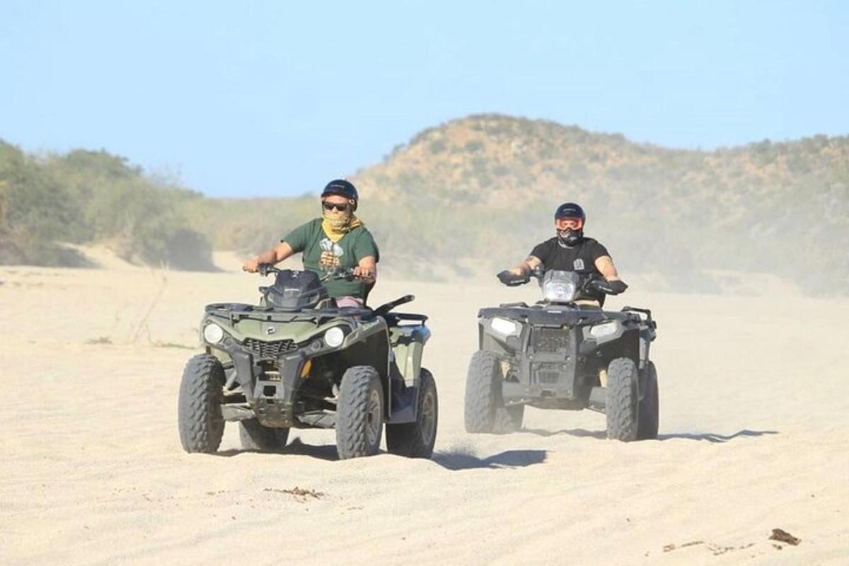 two people riding on atvs in the desert
