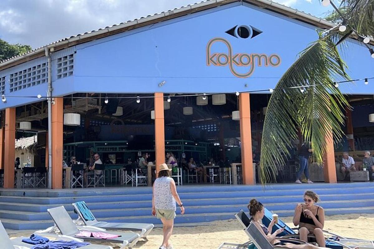 people sitting on the beach in front of a restaurant