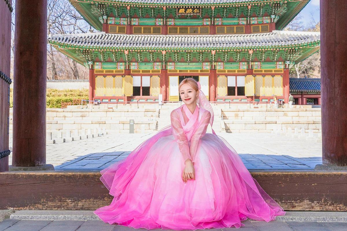 a girl in a pink dress sitting in front of a building
