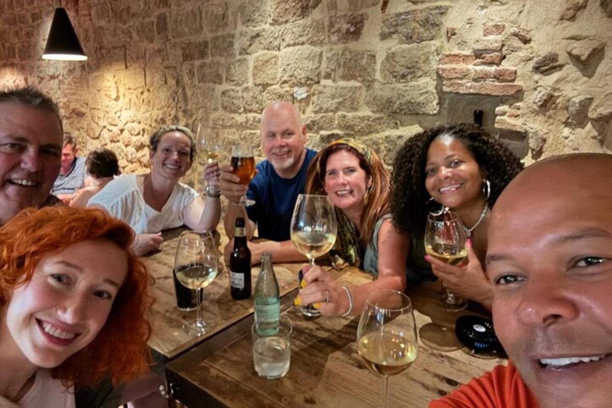 un gruppo di persone sedute attorno a un tavolo con bicchieri di vino