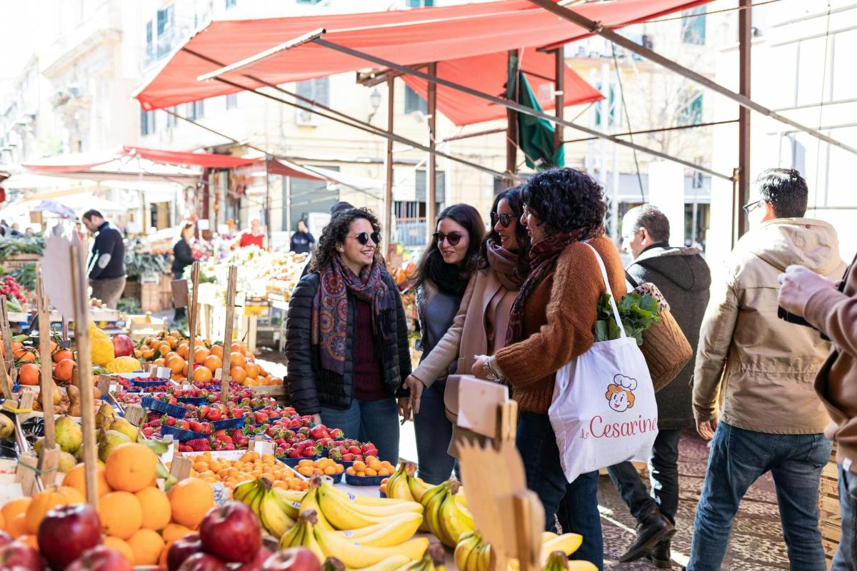 sekumpulan wanita berdiri di pasar dengan buah-buahan dan sayur-sayuran