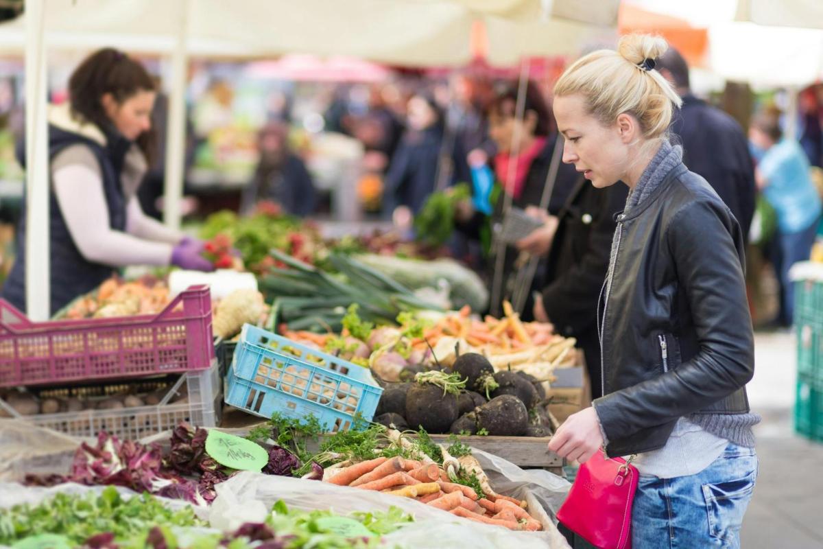 Una mujer parada en un mercado mirando verduras