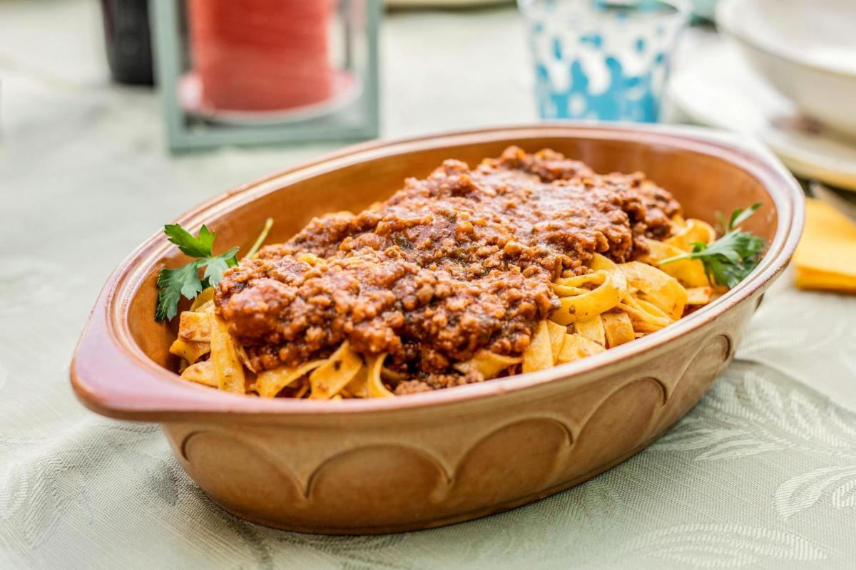 un bol de pasta amb carn i salsa a la taula