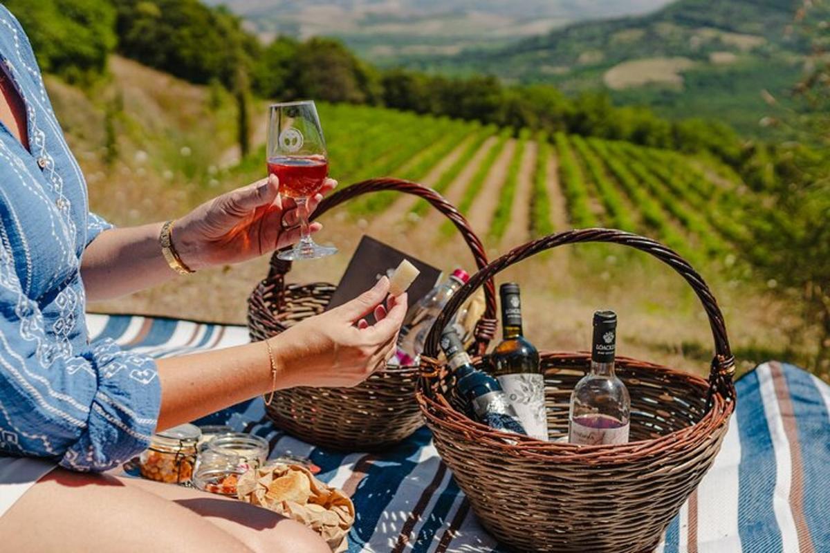 una donna che tiene in mano un bicchiere di vino e cesti di bottiglie di vino