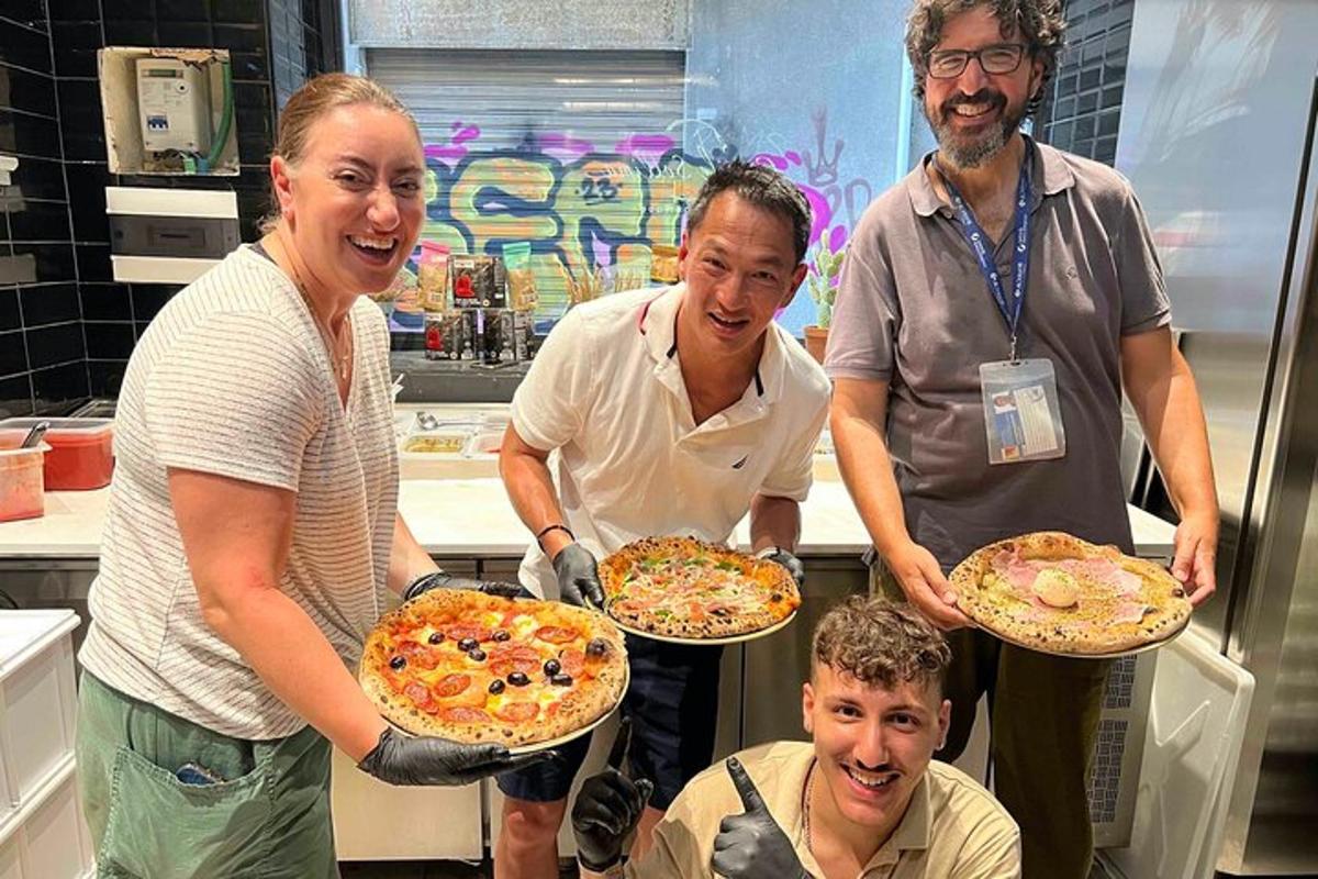 skupina lidí držících pizzy v kuchyni