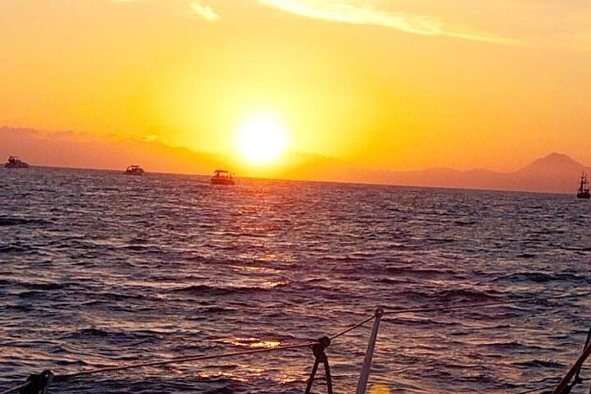 a boat in the ocean with the sunset in the background
