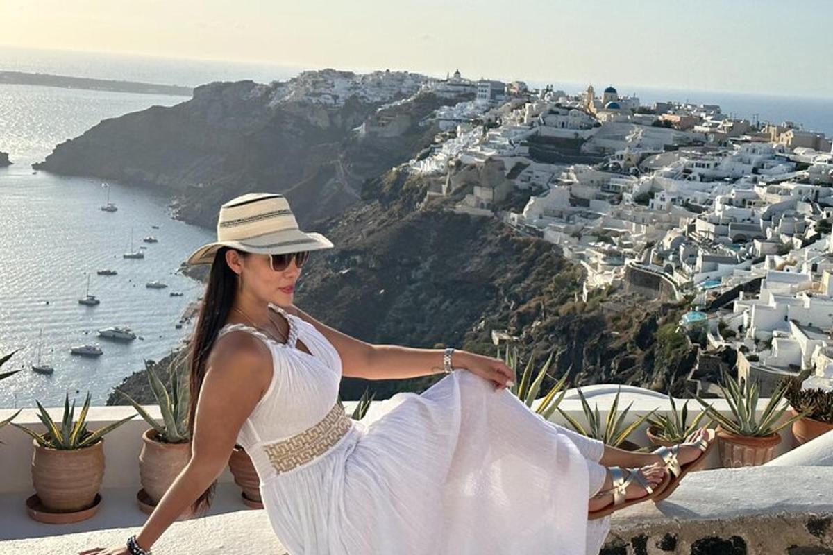 uma mulher de vestido branco e chapéu sentada em uma saliência