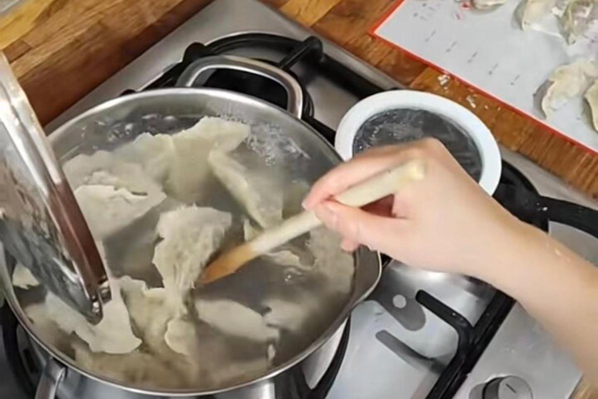 seseorang mengacau periuk makanan di atas dapur