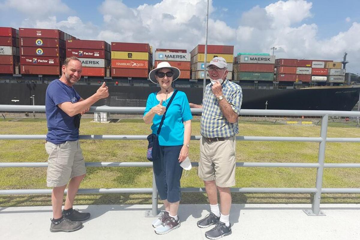 three people standing in front of a fence in front of a ship