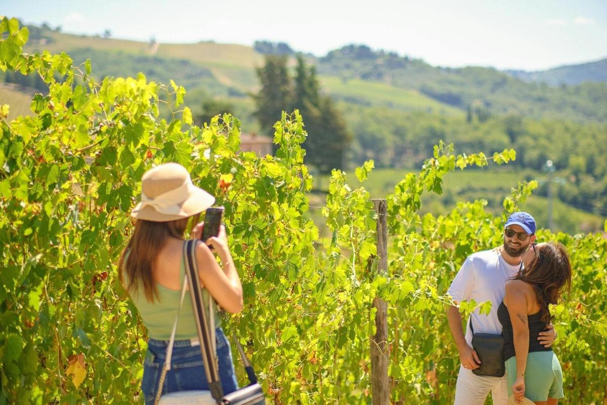 una donna che scatta una foto a un gruppo di persone in un vigneto
