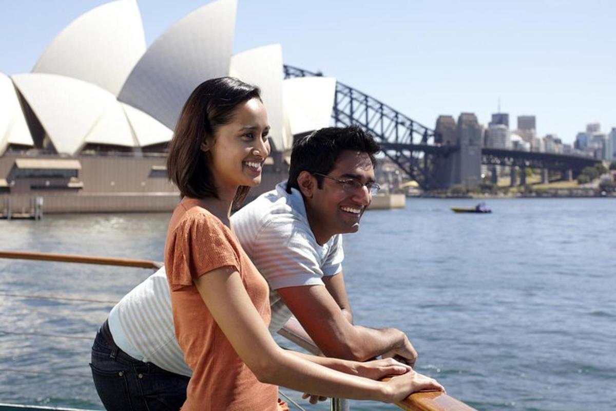 um homem e uma mulher em um barco em frente à ópera