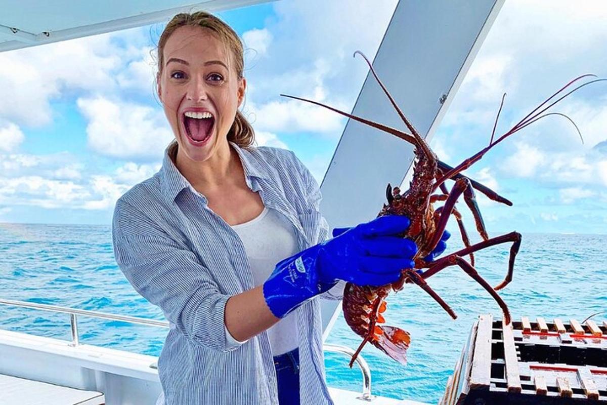 a woman holding a lobster on a boat