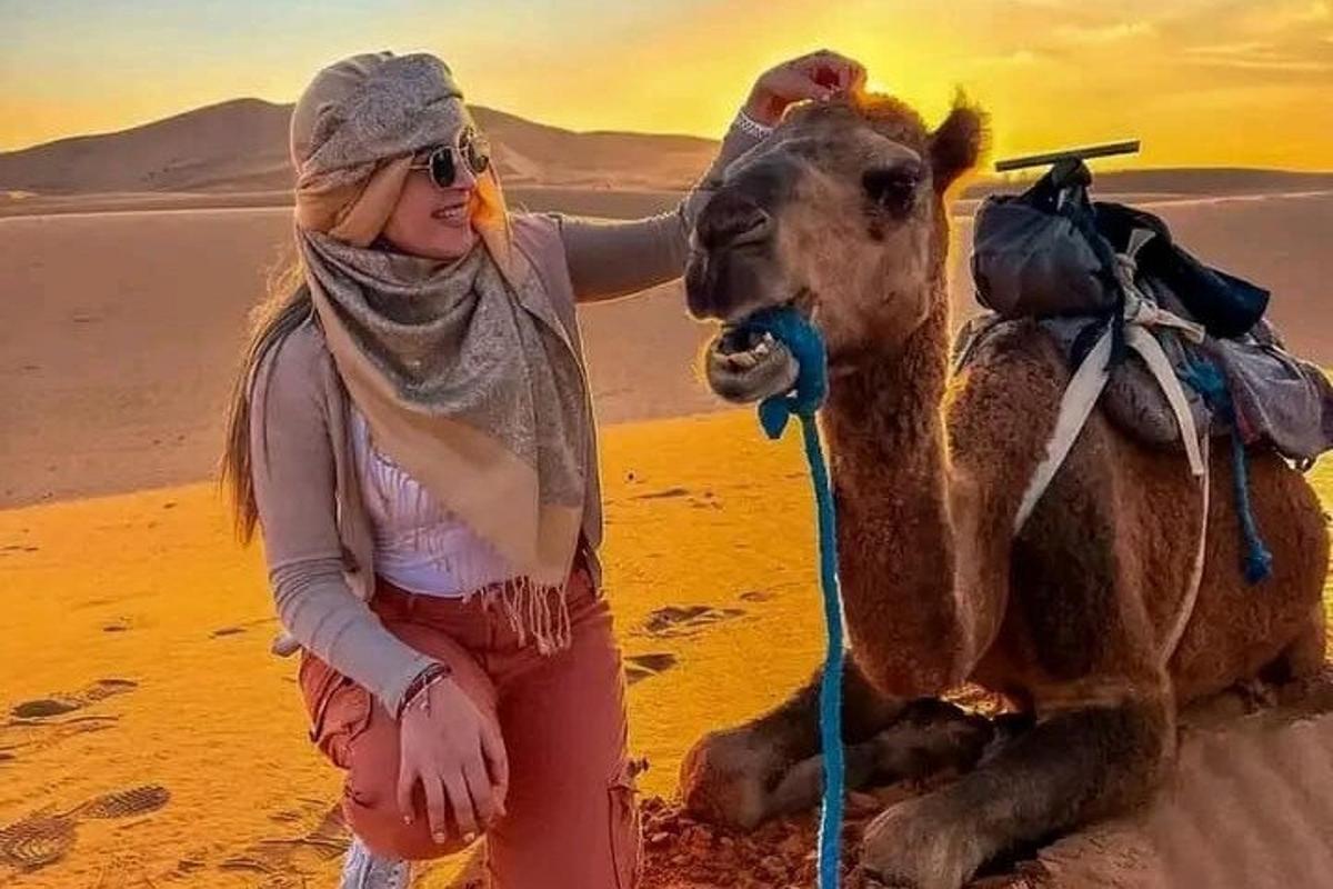 a woman standing next to a camel in the desert