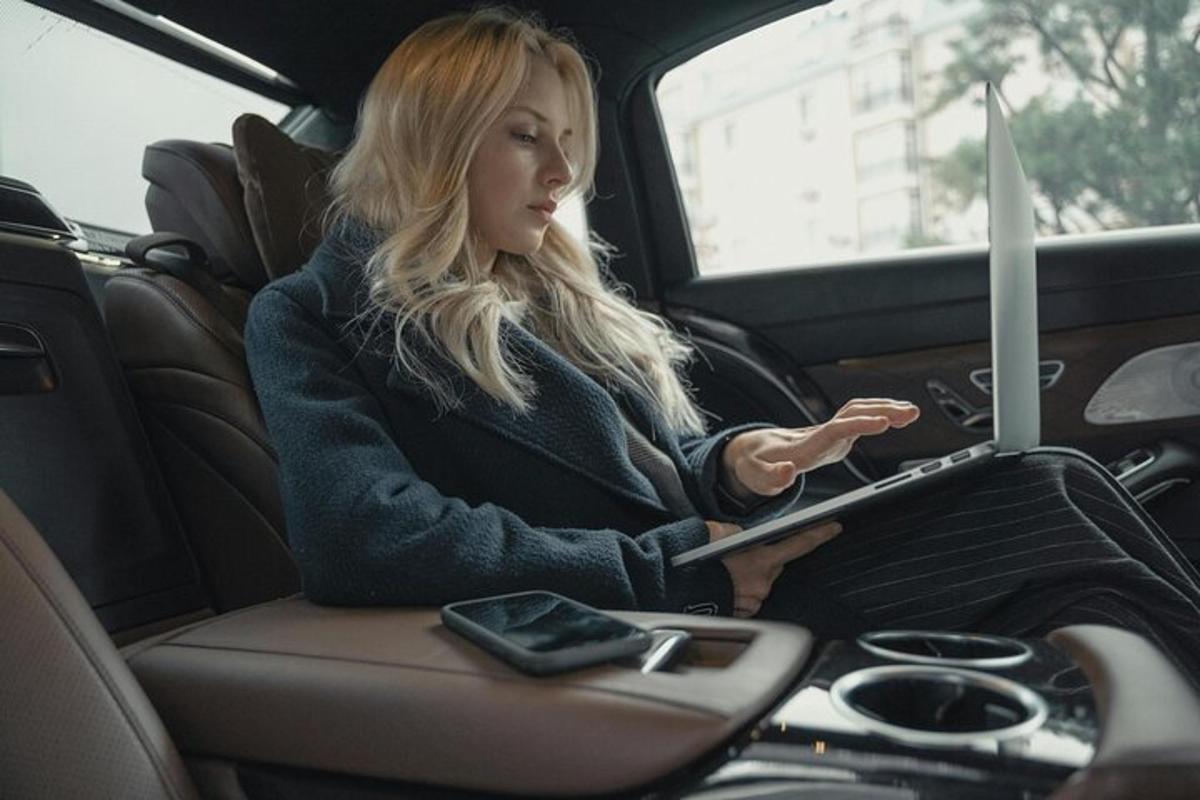 žena sedící na zadním sedadle auta s notebookem