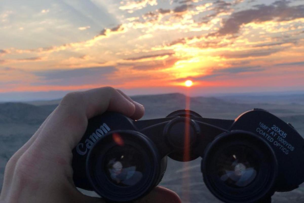 una persona che tiene in mano una macchina fotografica con il tramonto sullo sfondo