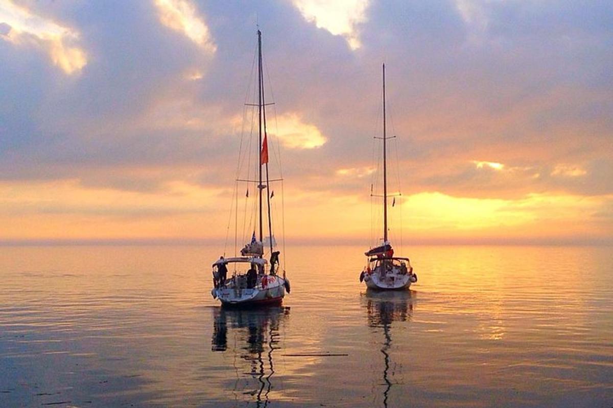 dos vaixells estan asseguts a l'aigua a la posta de sol