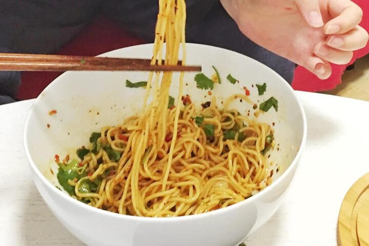 a person eating a bowl of noodles with chopsticks