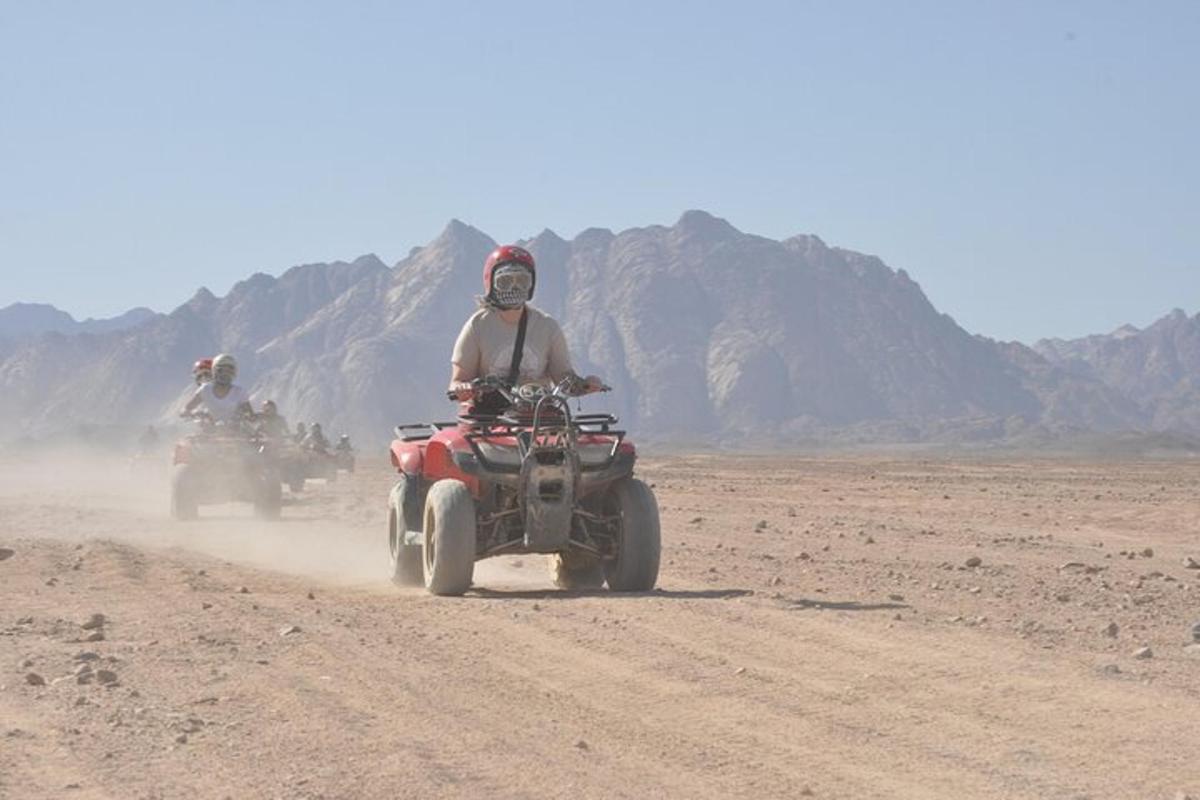 due persone in sella a quad su una strada sterrata nel deserto