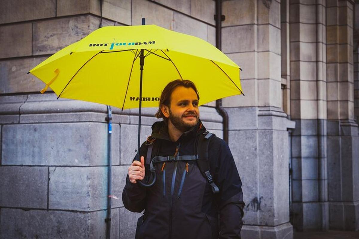 Maður heldur á gulum regnhlíf fyrir framan byggingu
