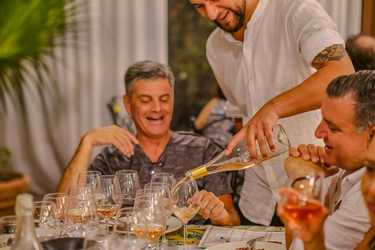 un uomo sta versando il vino nei bicchieri a un tavolo