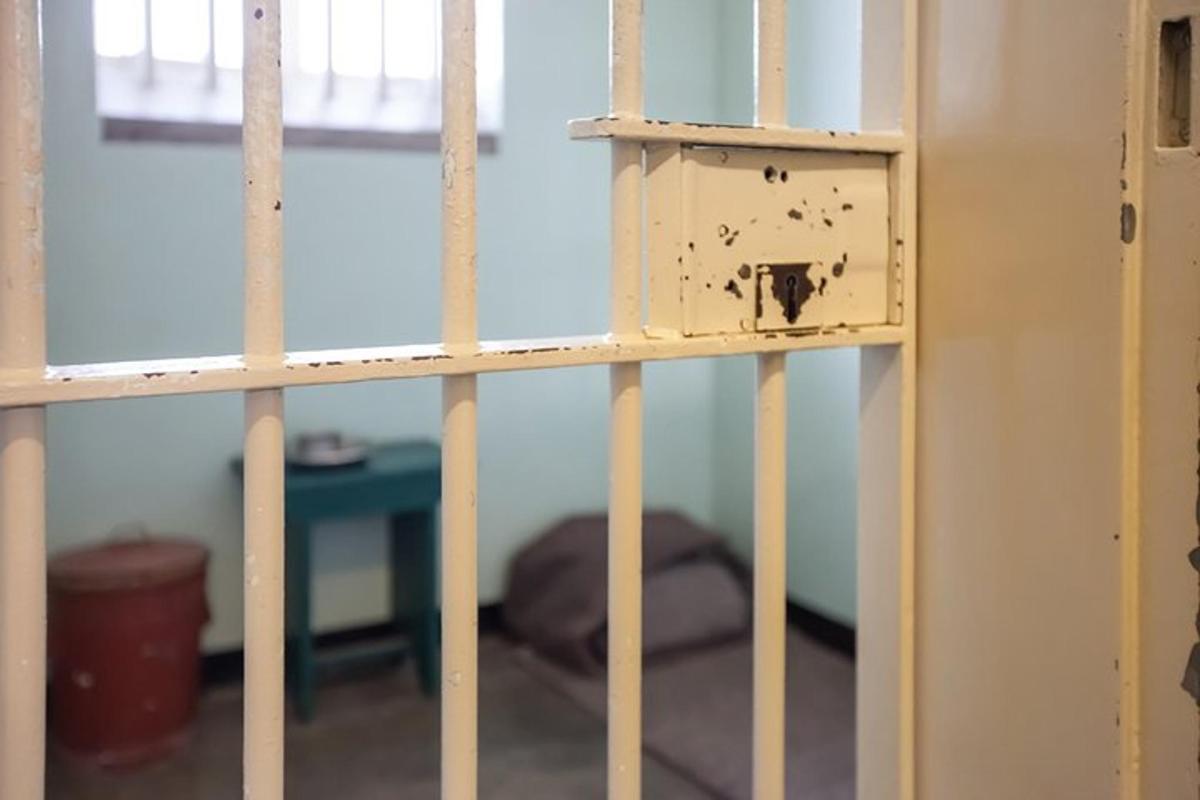 una porta aperta di una cella di prigione con un letto