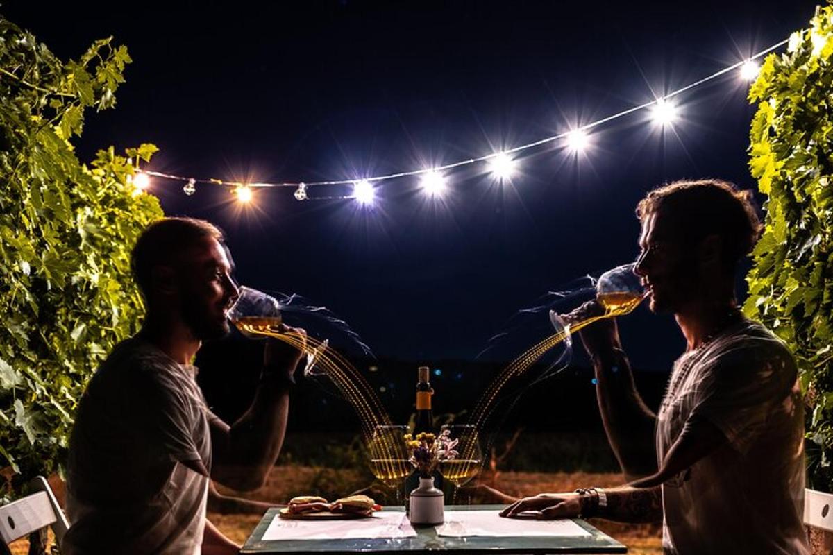 a man and woman drinking wine at a table at night