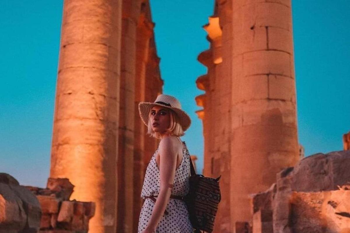 una donna con un cappello in piedi davanti alle colonne
