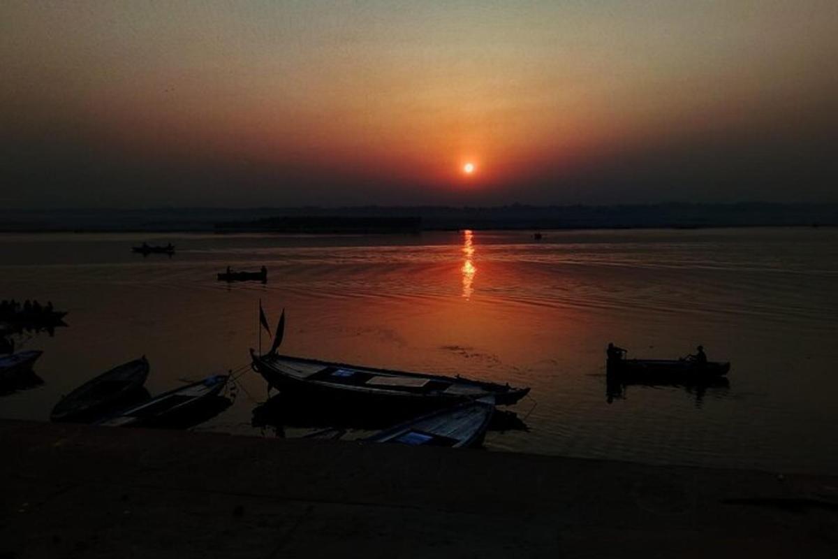 una posta de sol sobre un riu amb vaixells a l'aigua