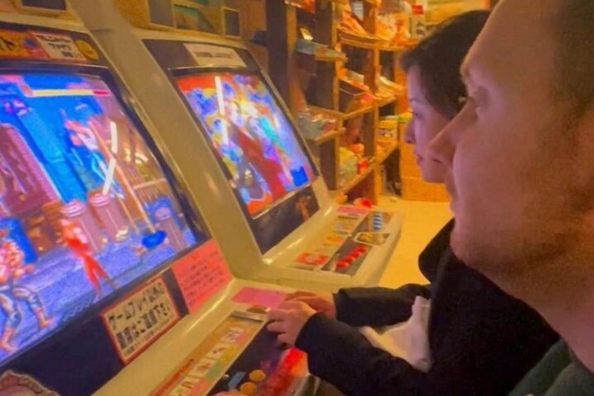dva lidé hrající videohru na pinballovém automatu