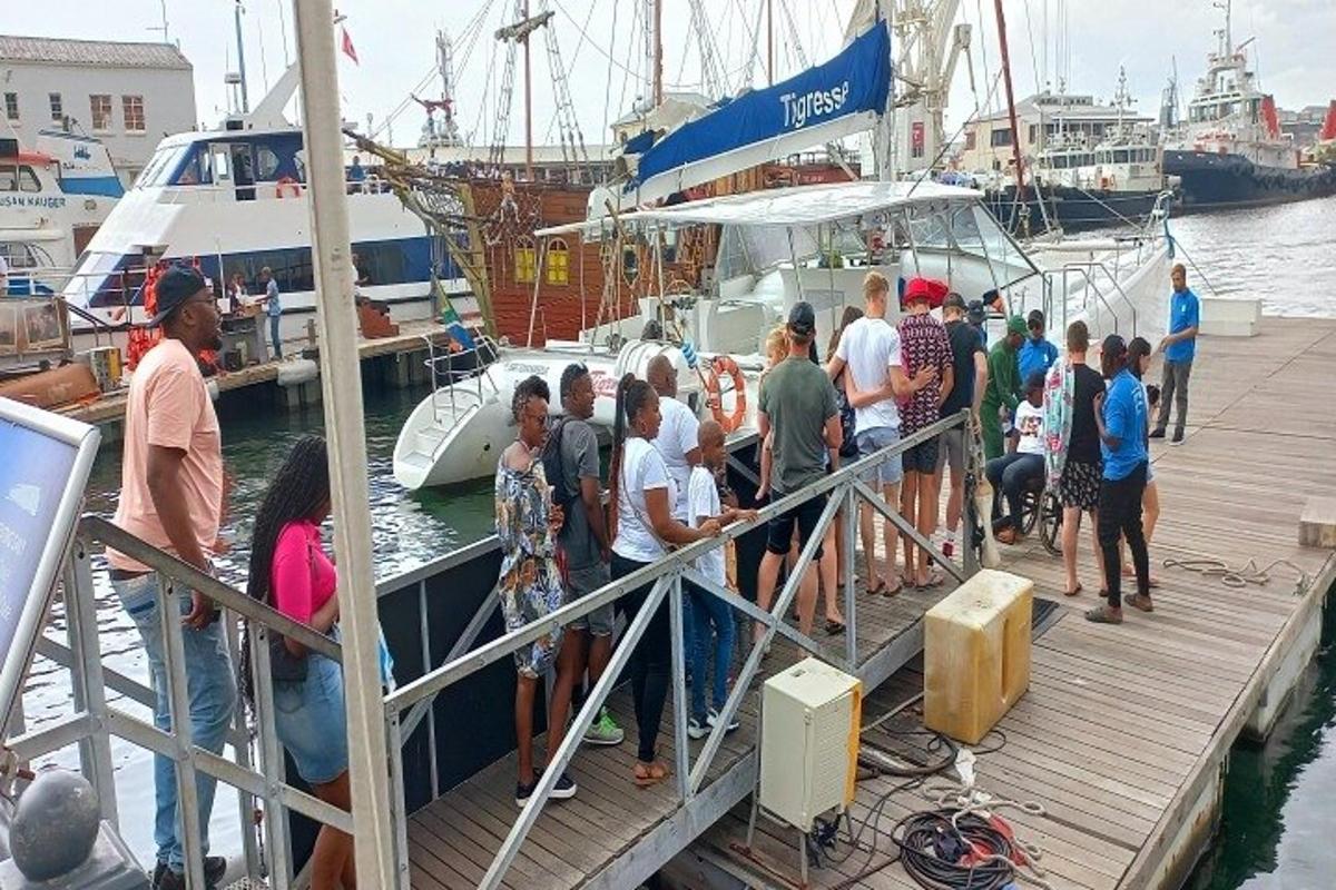 um grupo de pessoas em pé em uma doca ao lado de um barco