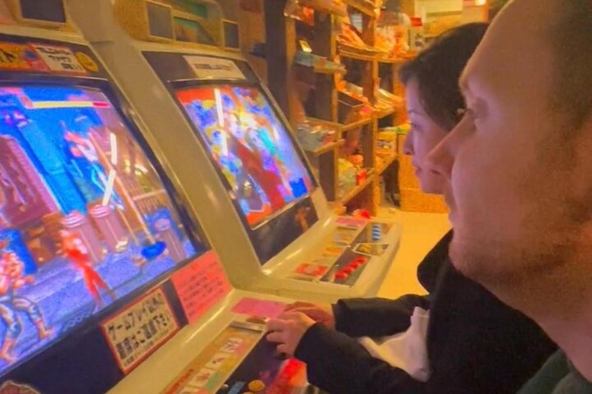 dva lidé hrající videohru na pinballovém automatu