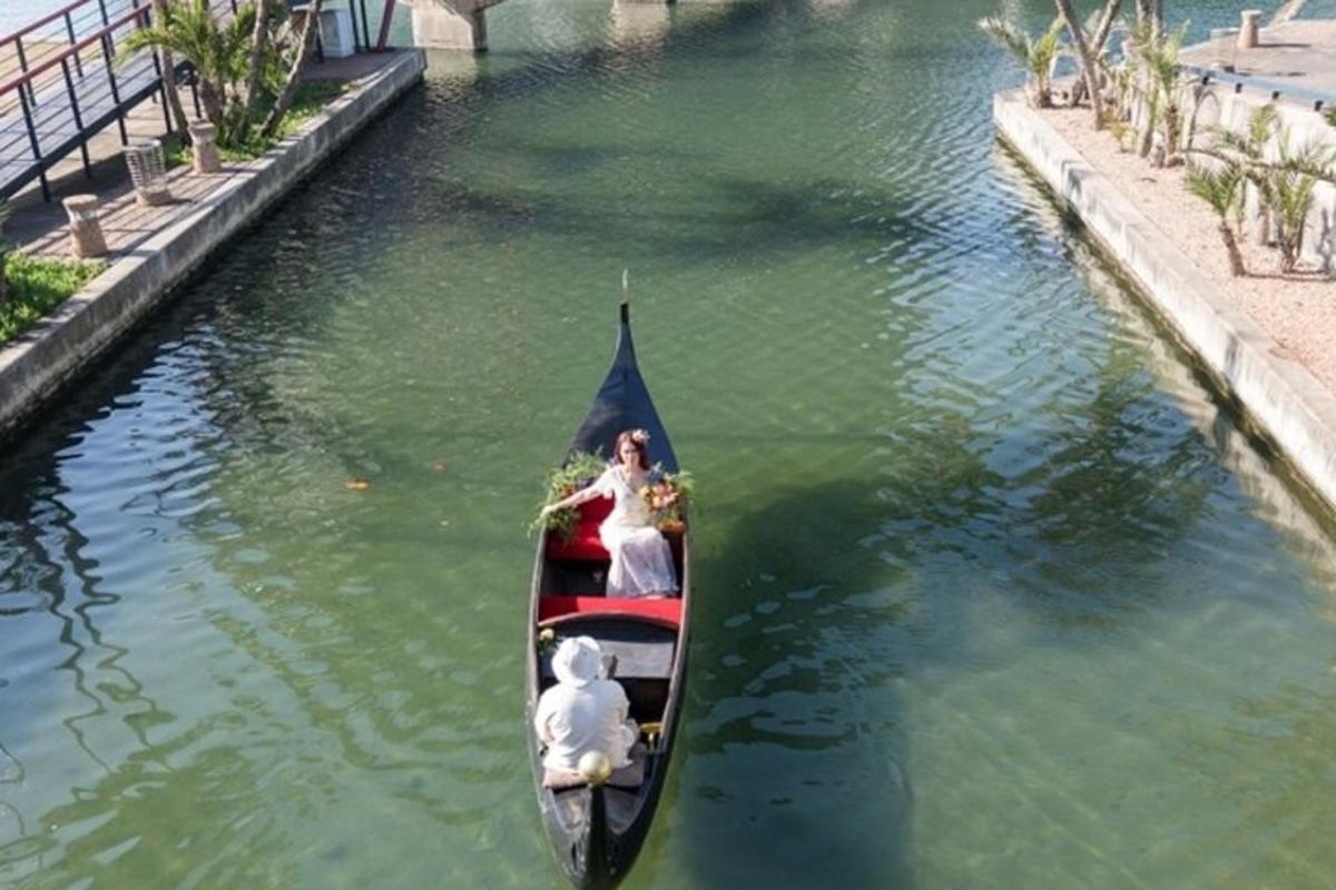 a bride and groom in a gondola on a canal