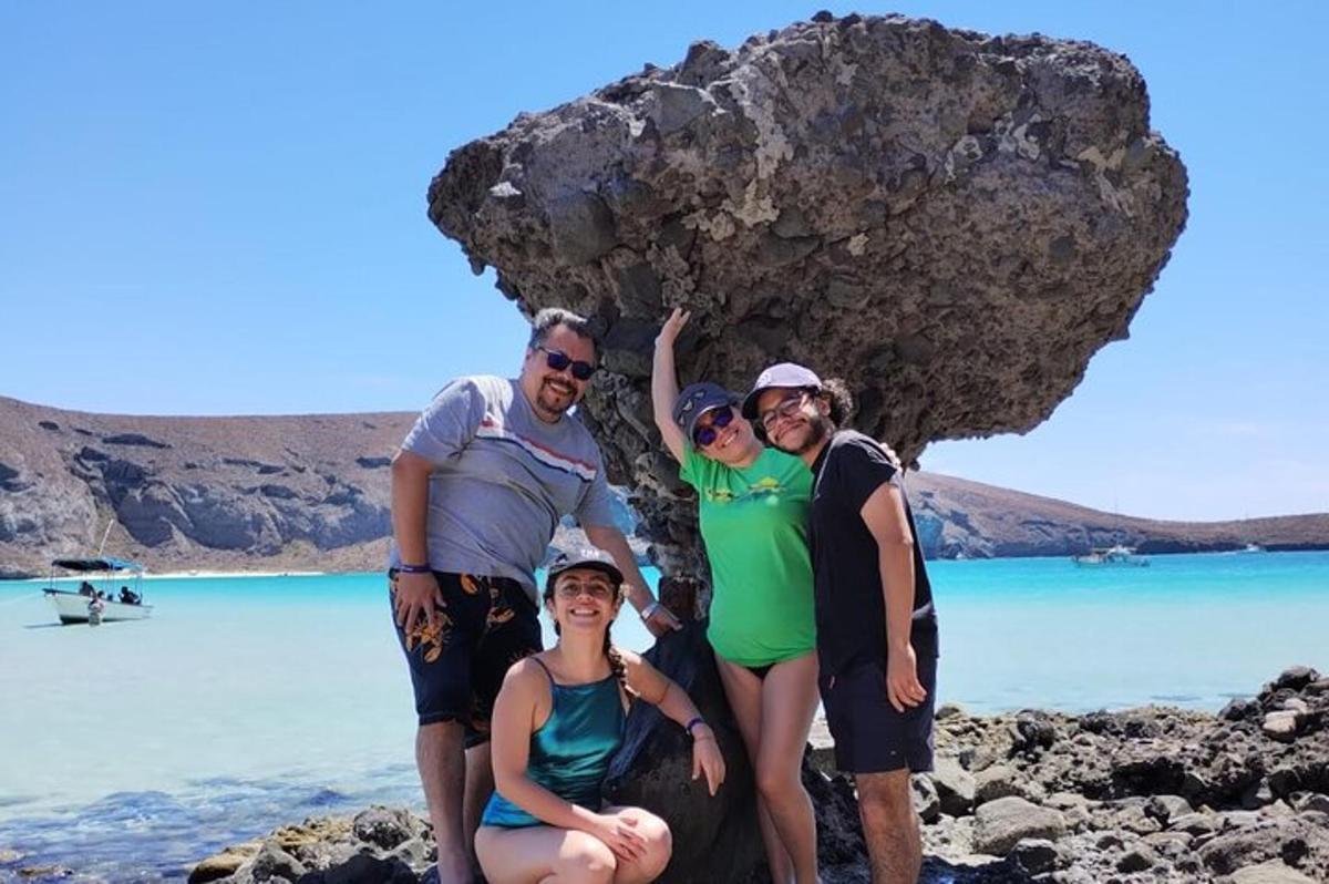 um grupo de pessoas em pé ao lado de uma rocha na praia