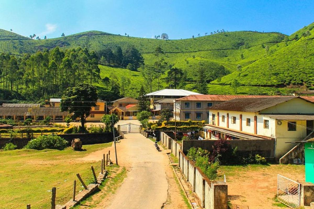 a dirt road in a village with mountains in the background