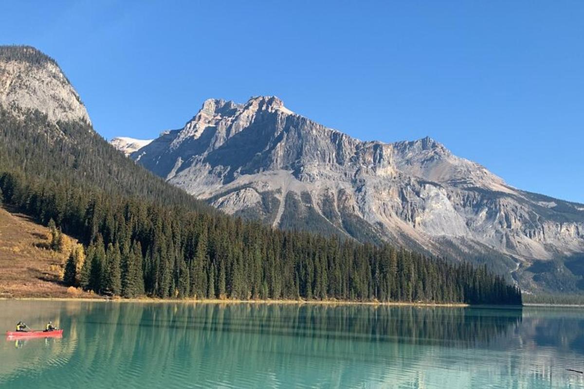 Dos personas en un bote en un lago con una montaña.