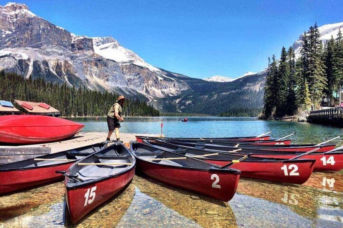 Un hombre de pie junto a un montón de barcos en un lago.
